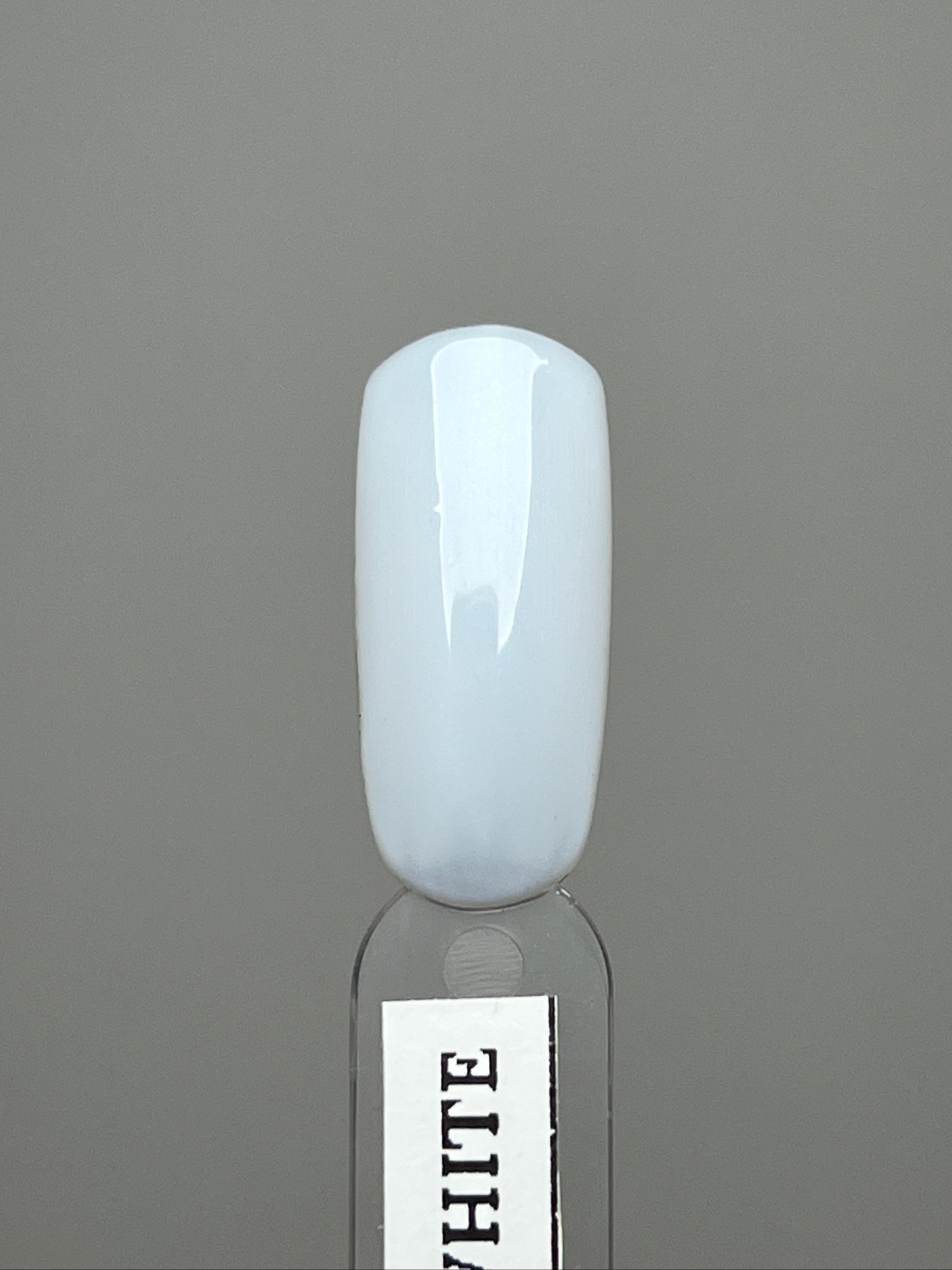 milky white nail swatch over a gray background