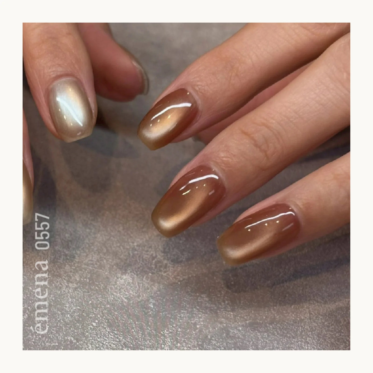 Close-up of hands with brown nail polish on a textured surface, featuring the brand 'emena'.