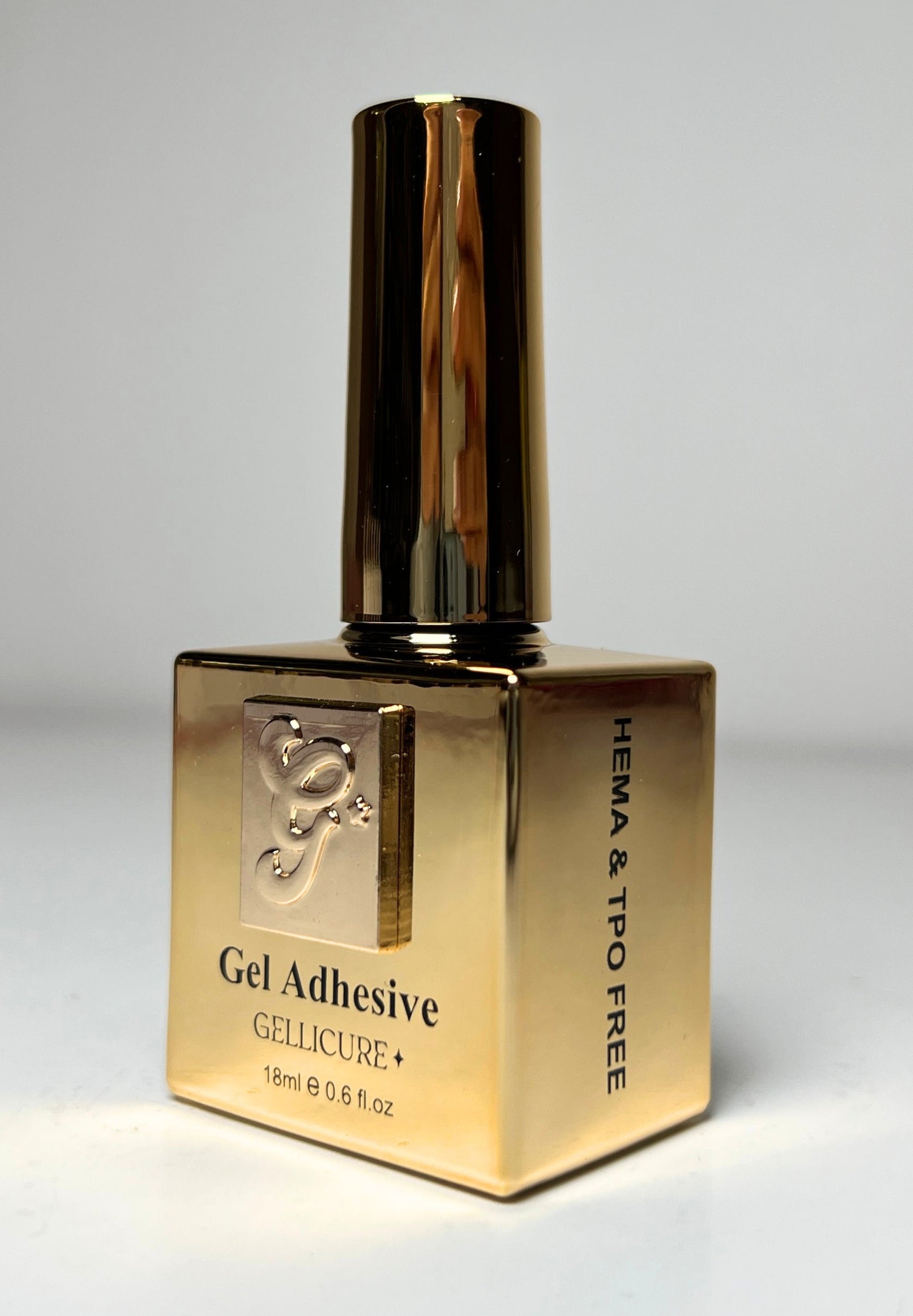 Gold bottle of Gel Adhesive on a gray background